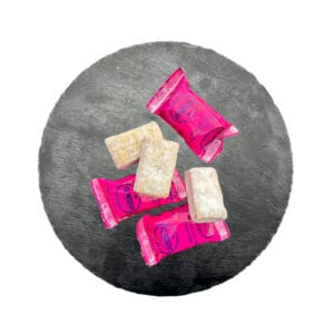 Knusprige spanische Toffees in pinken Verpackungen auf einem schwarzen Steinuntergrund, typisch für spanische Süßigkeiten und Dauerhaftigkeit.