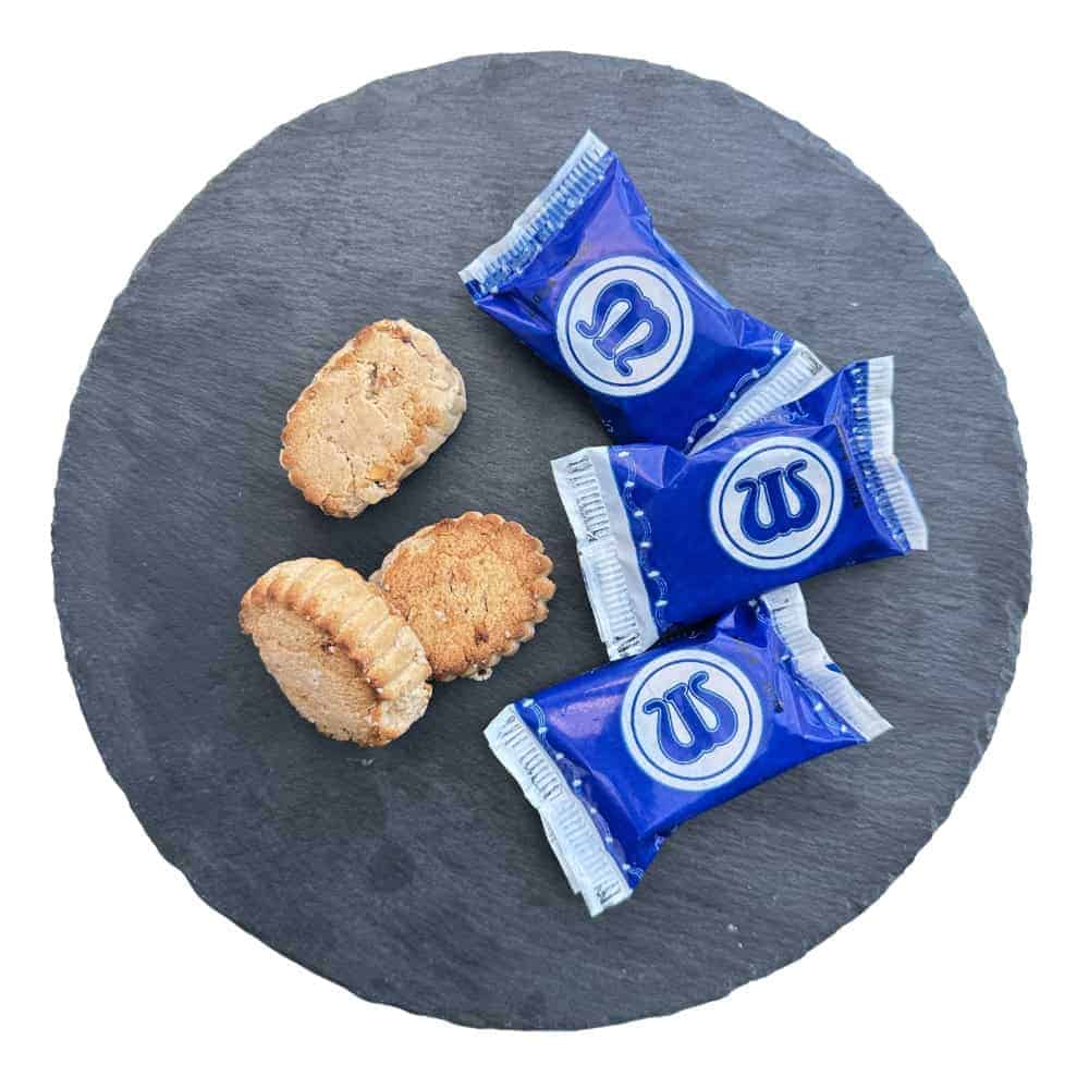 Knusprige spanische Sandkekse auf schwarzem Steinteller, verpackt in blauen Mareni-Wrappings, ideal für authentisches spanisches Gebäck.