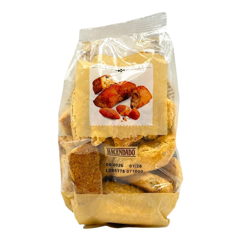Mareni Mandelpaste in transparenter Verpackung mit Mandeln und Mandelstücken im Hintergrund.