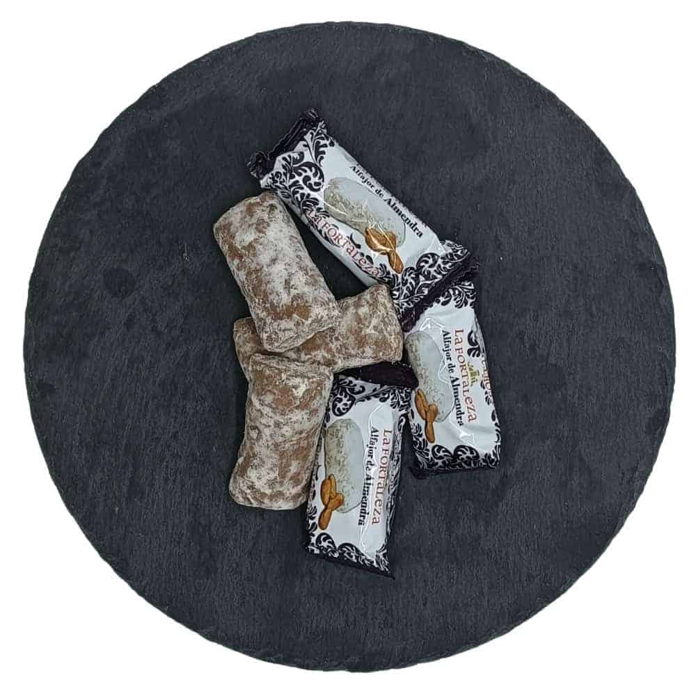 Spanisches Mandelhoniggebäck (Alfajor de Almendra) auf dunklem Steinuntergrund, einzelne Stücke mit Zuckerpuder.