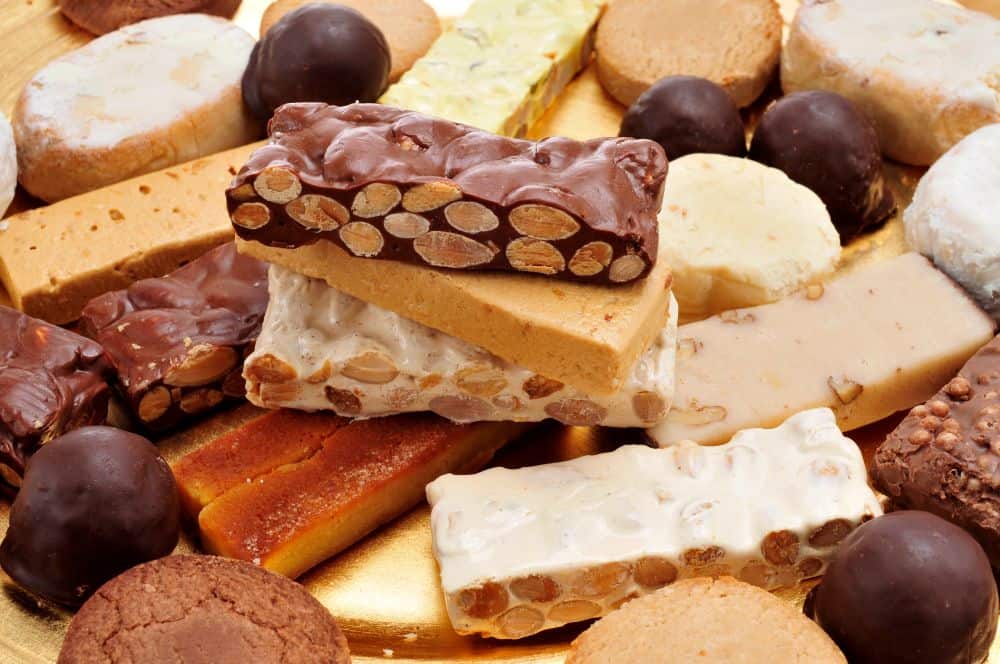 Auslage mit verschiedenen Schokoladen- und Nougat-Schnitten sowie Biscuit- und Karamellstäbchen, appetitlich arrangiert.